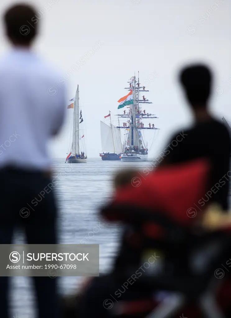 Sailing ships head to sea as people watch the Parade of Sail conclusion of the 2007 Tall Ships festival in Halifax, Nova Scotia.