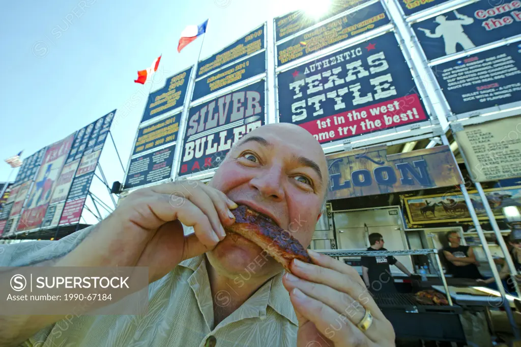 A visitor enjoys pork ribs at Toronto ribfest in the Centennial Park during Canada Day celebrations.