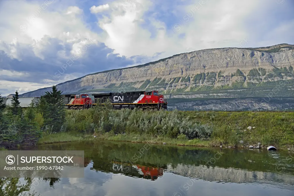 A Canadian National Freight Train pulling a load of rail cars east along a rail line through the rocky mountains of Jasper National Park in Alberta, C...