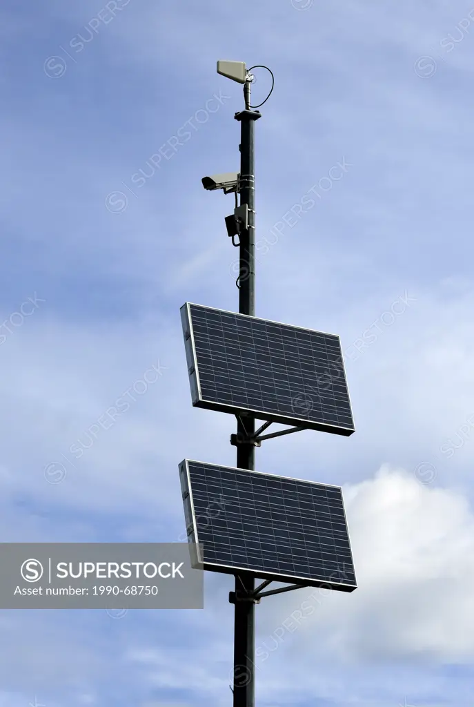 A vertical image of a remote highway camera with solar pannel operating system against a sky background.