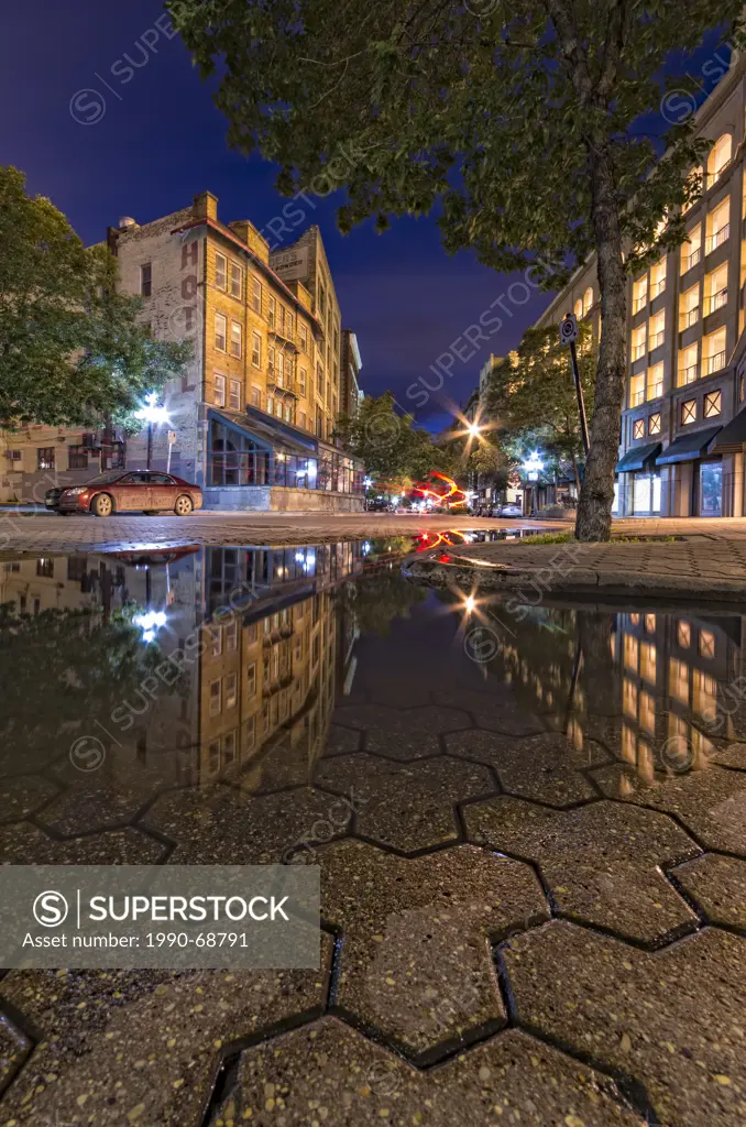 Old heritage buildings reflecting in a puddle in the Exchange District of Downtown Winnipeg at dusk. Manitoba, Canada.