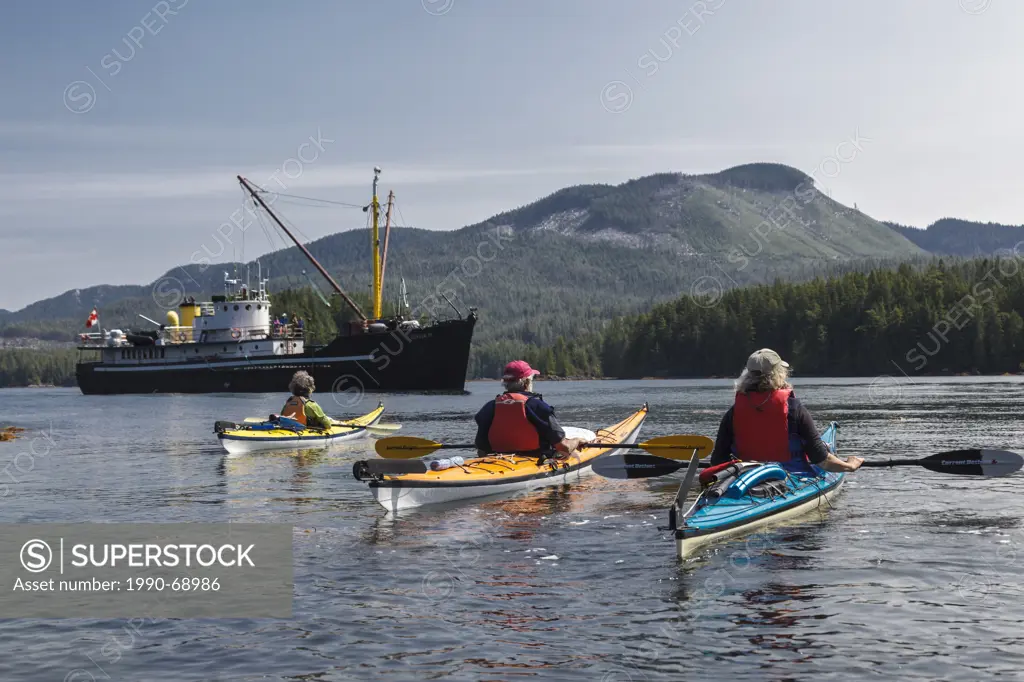 Three kayakers await pickup by the supply ship the Uchuck 111 at Flynn´s Cove, Nootka Island, British Columbia, Canada. Model Released