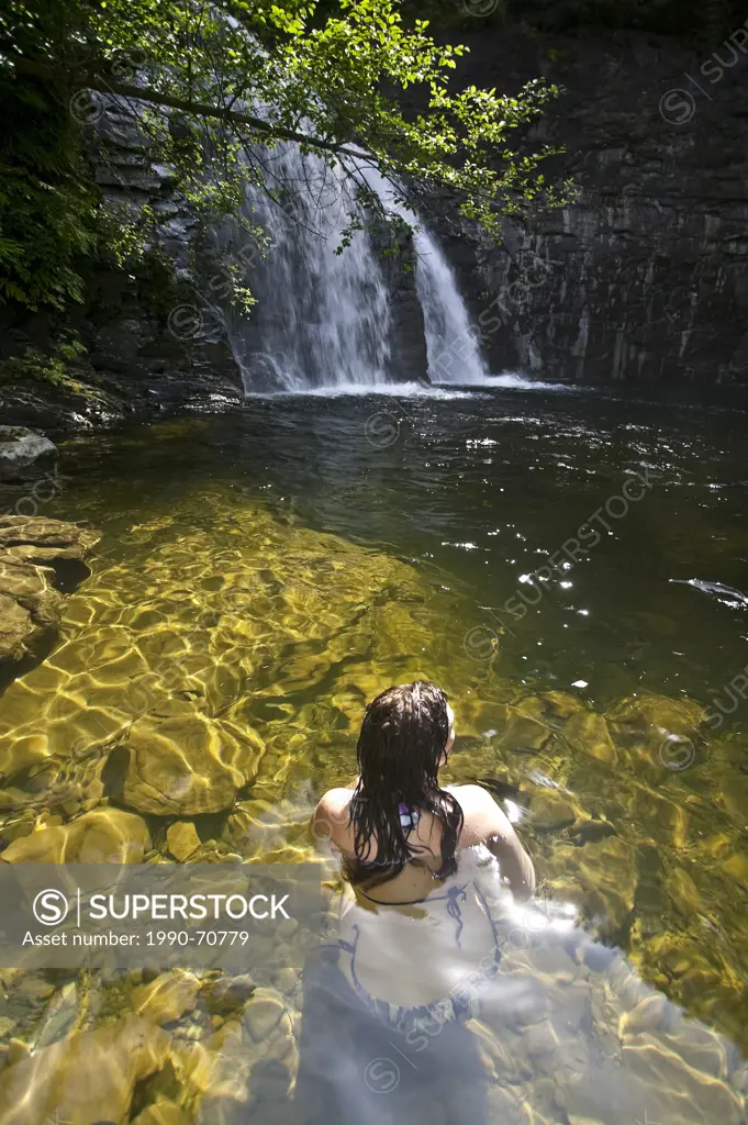 Young women cools off at The Trent River falls, Courtenay, The Comox Valley, Vancouver Island, British Columbia, Canada