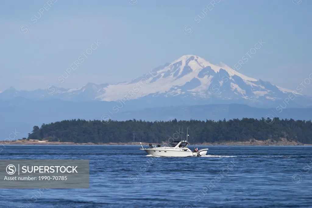 A boat cruises through waters in Haro Strait with Mt. Baker in the background. Gulf Islands, British Columbia, Canada