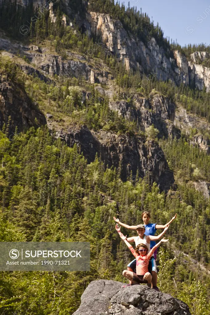Three girls strike pose while hiking up Lafferty Creek on Nahanni River, Nahanni National Park Preserve, NWT, Canada.