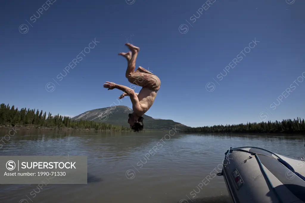 Man jumps from raft into Nahanni River, Nahanni National Park Preserve, NWT, Canada.