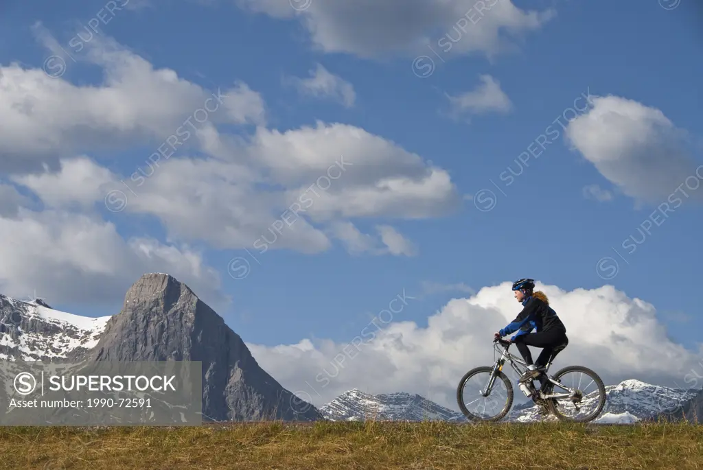 Female cyclist against mountains, Canmore, Alberta, Canada