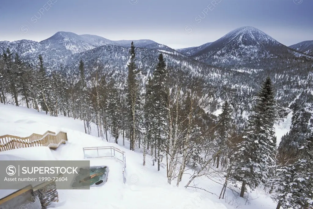 woman floating in outdoor hot tub in winter, ChicChocs Mountains, Quebec, Canada