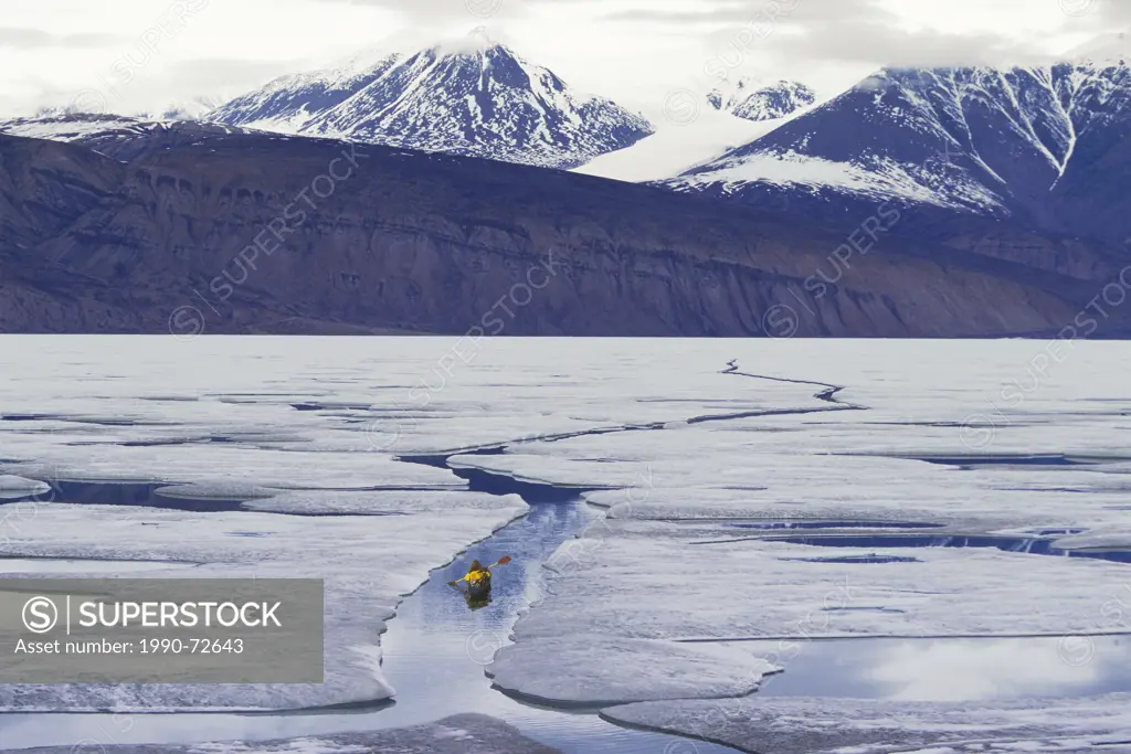 Kayaker in open lead (crack) in sea ice, Tanquary Fiord, Quttinirpaaq National Park, Ellesmere Island, Nunavut, Canada