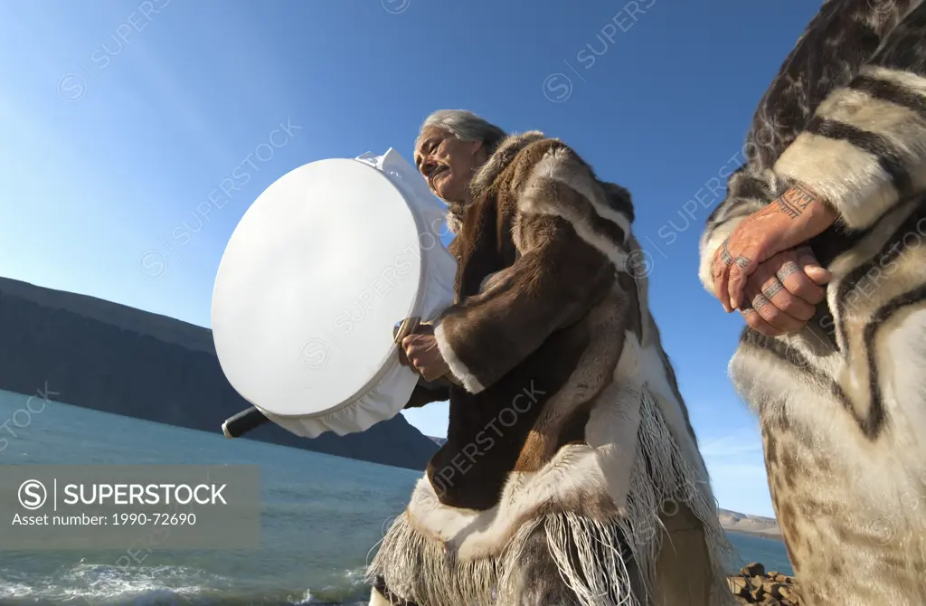 Inuit couple in traditional caribou skins drum dancing and singing, Devon Island, Nunavut, Canada