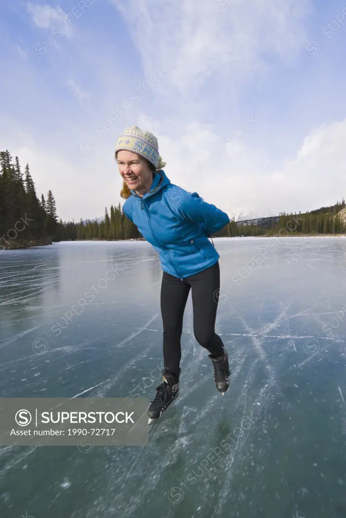 Woman skating on frozen lake, Camore, Alberta, Canada