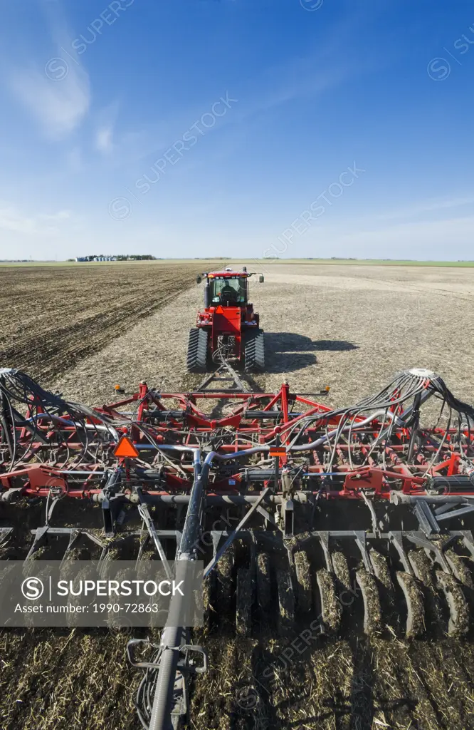 Moving tractor and and air till seeder planting soybeans in grain stubble, near Dugald, Manitoba, Canada