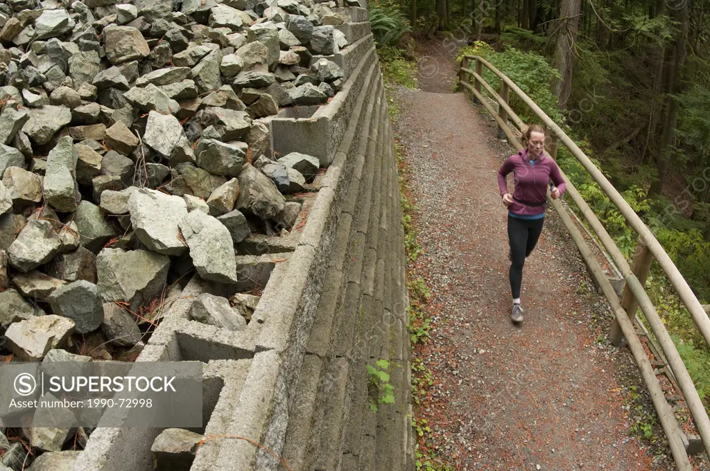 Woman trail running on the Capilano Pacific Trail, Capilano River Regional Park, North Vancouver, British Columbia, Canada