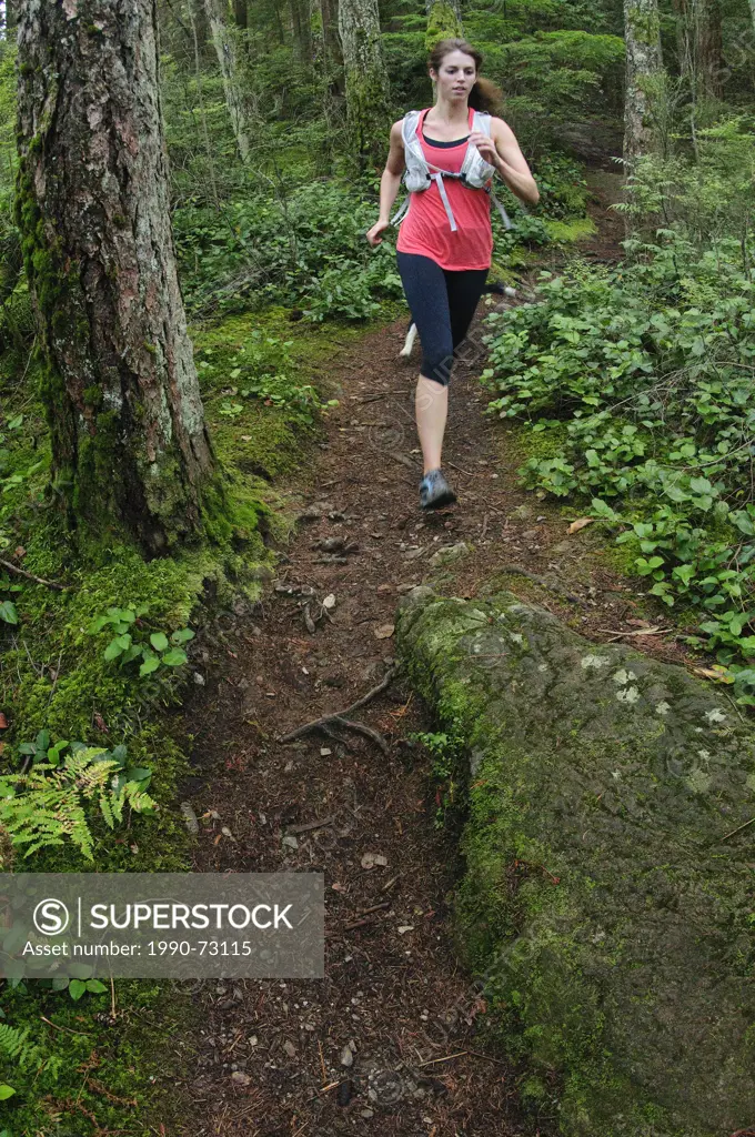 Woman trail running the Jug Island Trail. Belcarra Regional Park, Port Moody, British Columbia, Canada