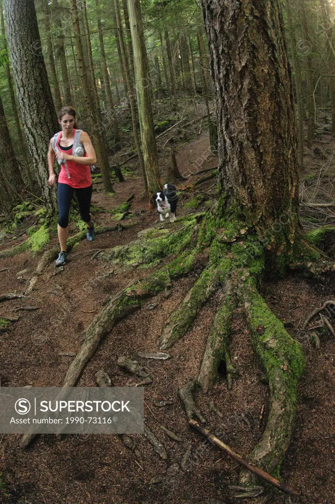Woman trail running the Jug Island Trail. Belcarra Regional Park, Port Moody, British Columbia, Canada