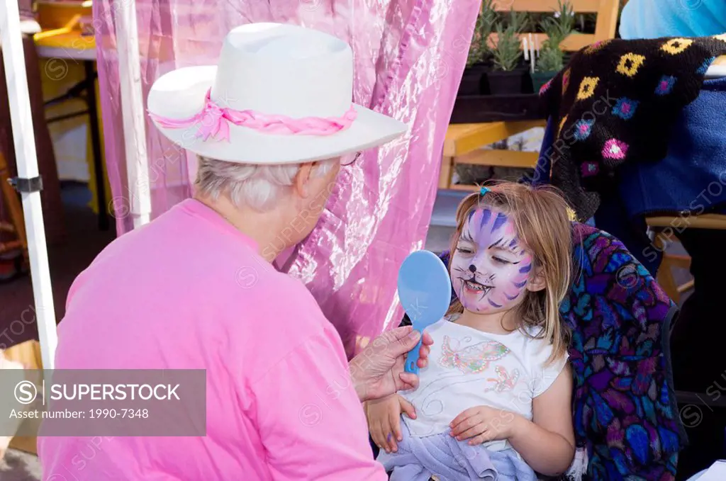 Girl gets her face painted at Saltspring Island Saturday Market, Gulf Islands, British Columbia, Canada