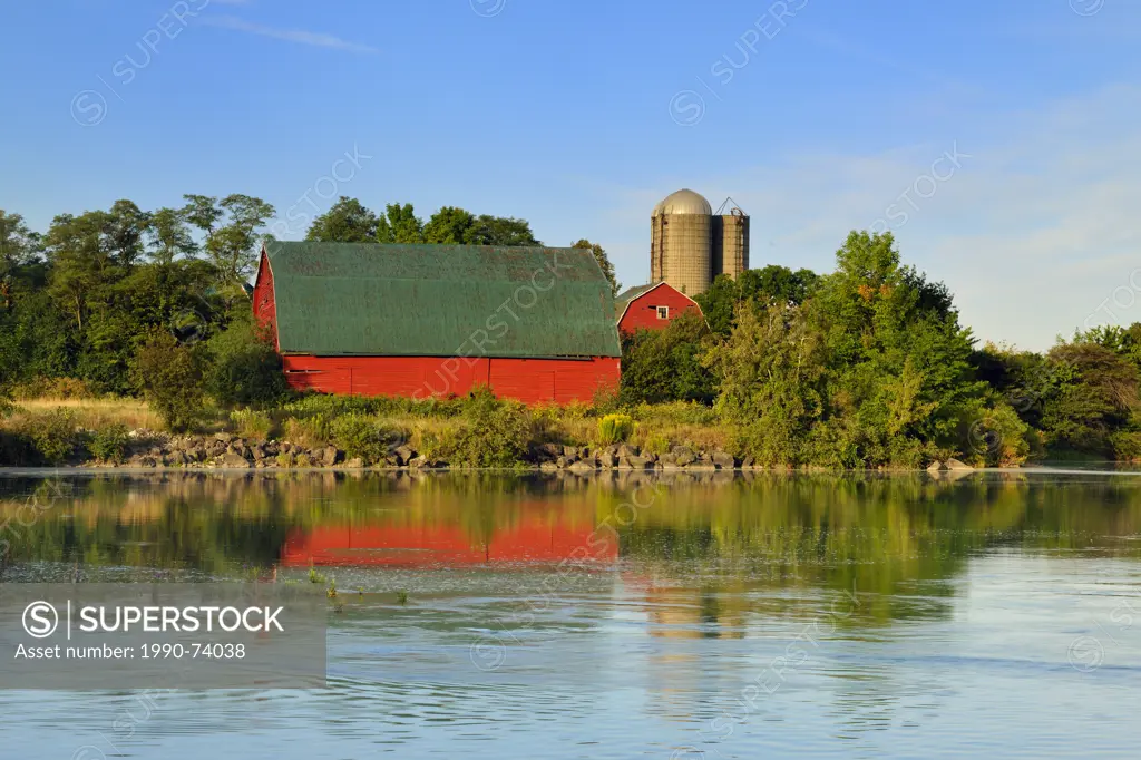 An aging red barn reflected into Gibson Lake waterway (hydro controlled) at dawn