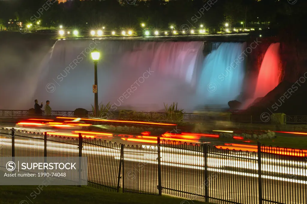 Nighttime at Niagara Falls- Coloured spotlights on the American Falls with traffic on the Niagara Parkway