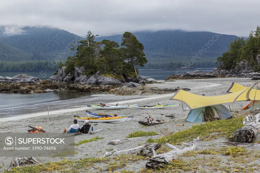 Two kaykers relax by their campfire on Benson Point after a days paddling off Nootka Island, on the west coast of British Columbia, Canada. No Release