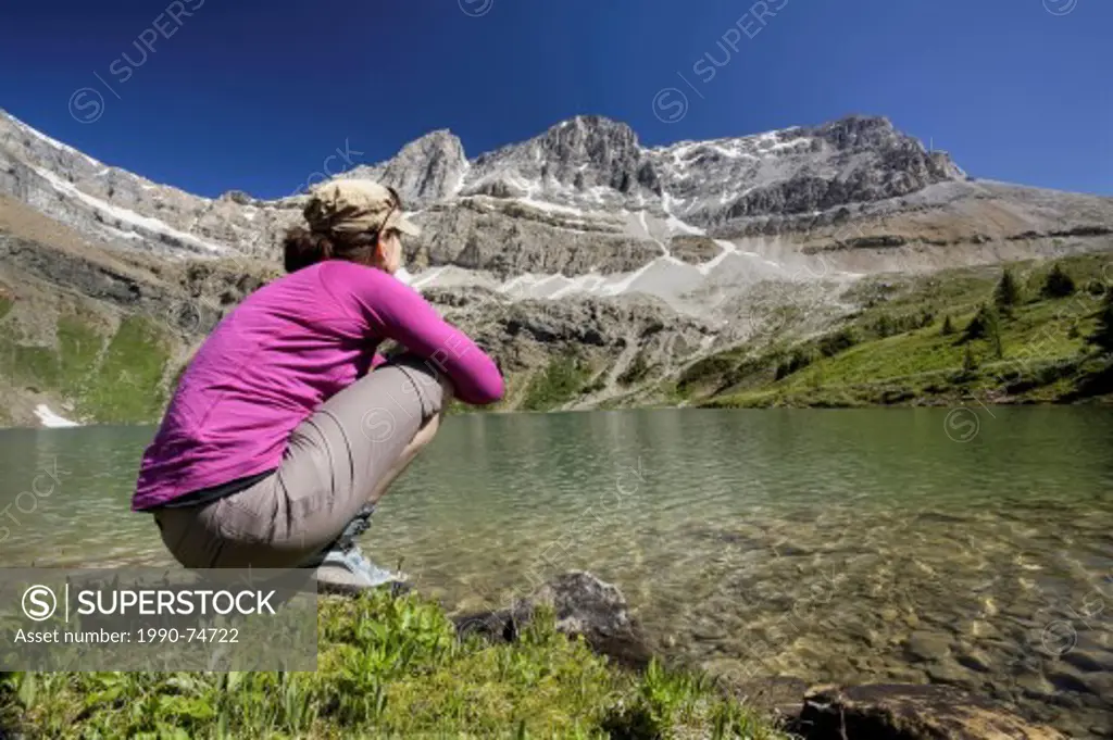 Woman crouching by Hidden Lake, Banff National Park, Alberta, Canada.