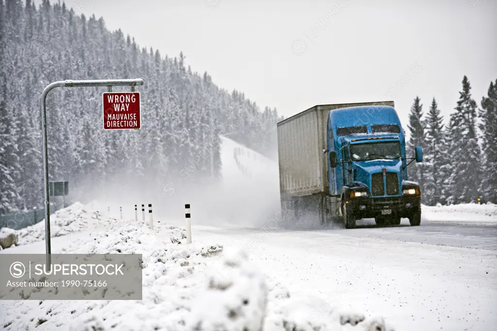 Wrong way sign and transport truck on Trans-Canada Highway in winter conditions near Lake Louise, Alberta, Canada.