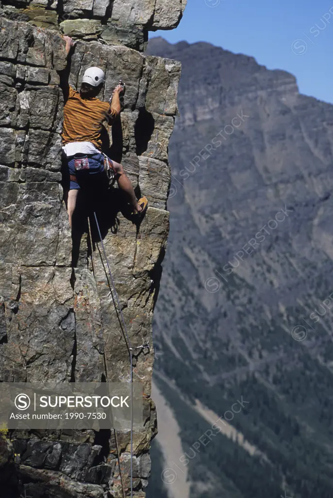 A young man clipping in on Cardiac Arete on Grand Sentinel, Alberta, Canada