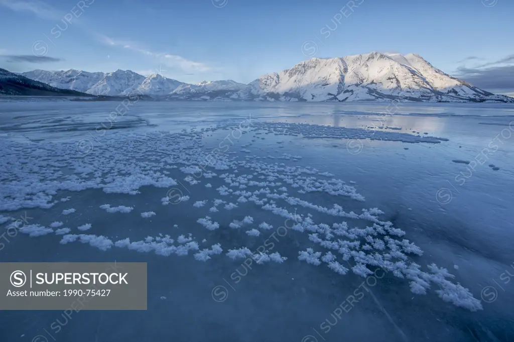 Ice crystals grow on the frozen surface of Kluane Lake with Sheep Mountain lighting up in the distance. Kluane National Park, Yukon.