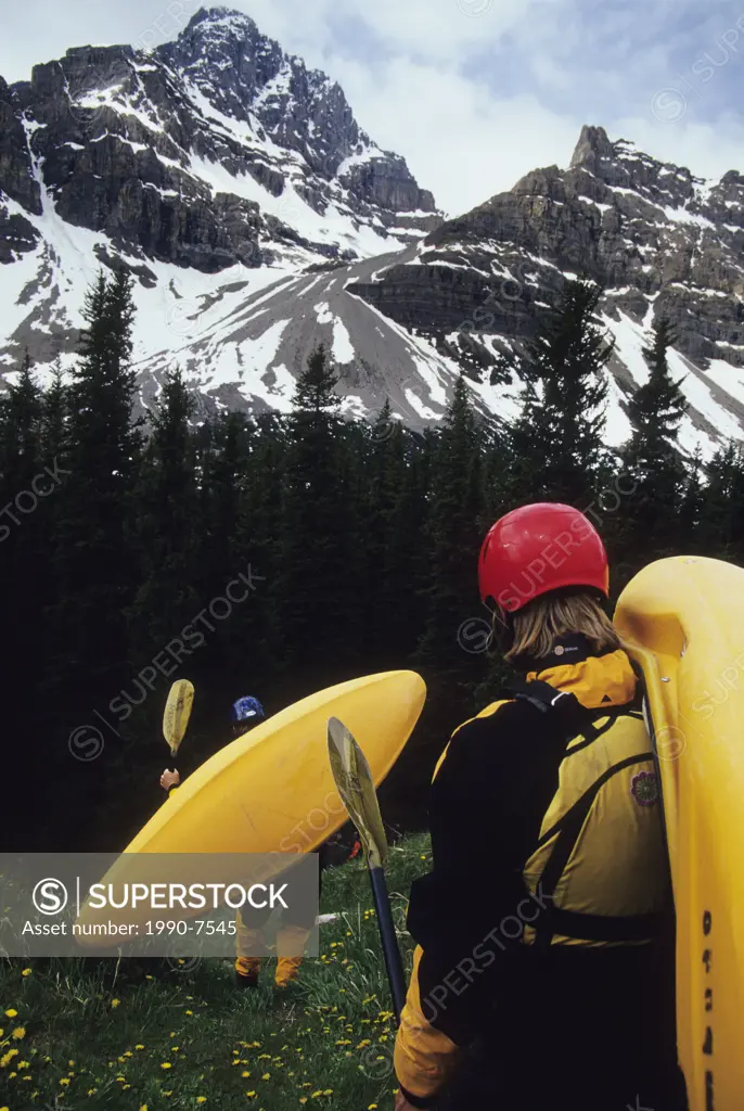 Kayakers hiking to put in on Bow River, Banff National Park, Alberta, Canada