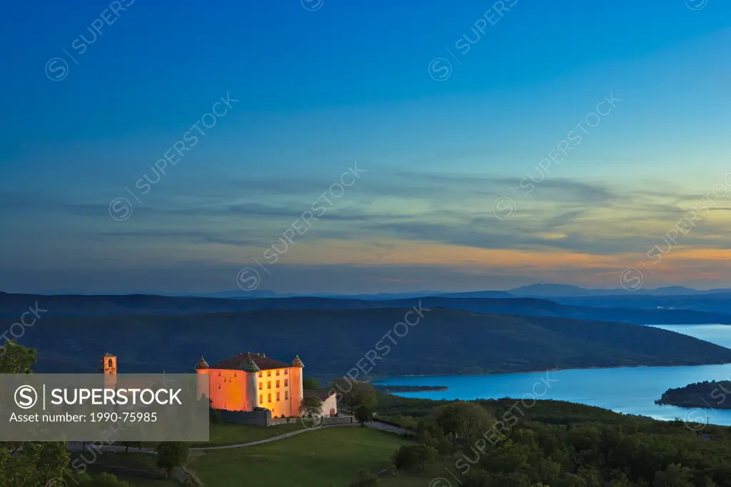 The restored 17th centure Chateau in the Village of Aiguines after sunset and backdropped by Lac de Ste Croix, Alpes due Haute, Provence, France, Euro...