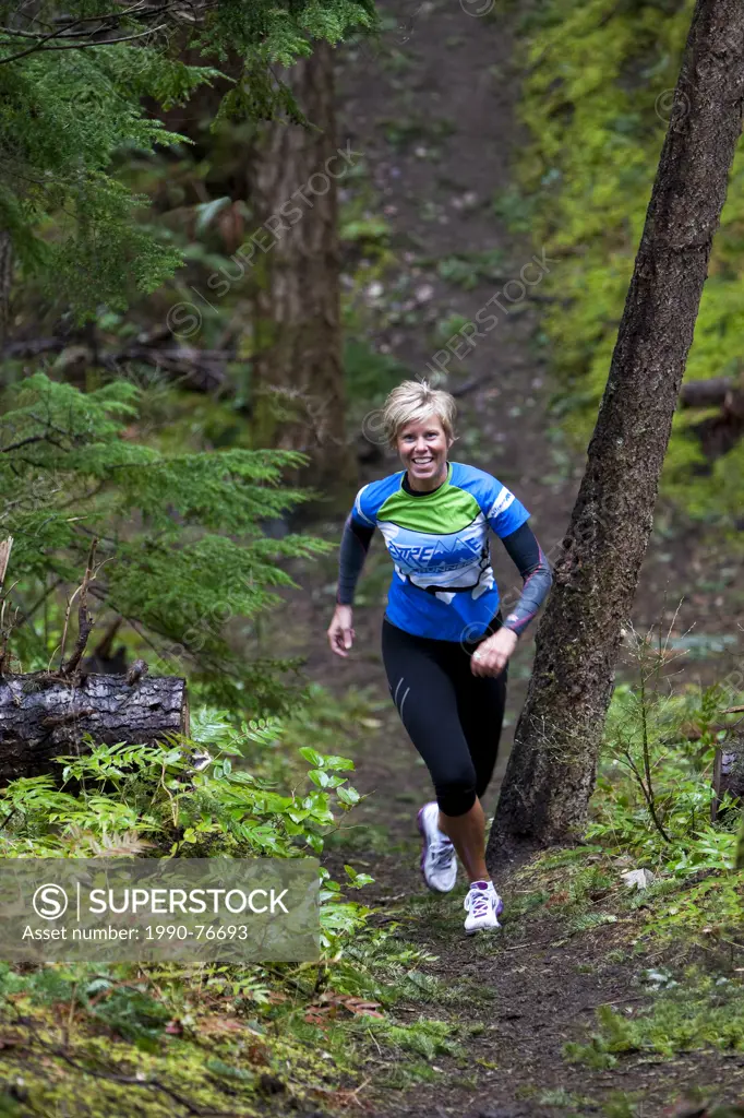 A woman runs up a hill in the trails around the Lazo Marsh in Comox. Comox, The Comox Valley, Vancouver Island, British Columbia, Canada.