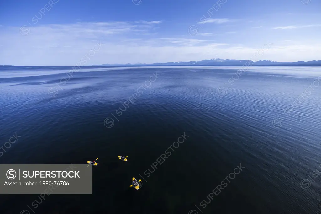 Kayakers skirt along the shoreline, looking south towards Vancouver Island, near Helliwell Bluffs on Hornby Island. Hornby Island, Northern Gulf Islan...
