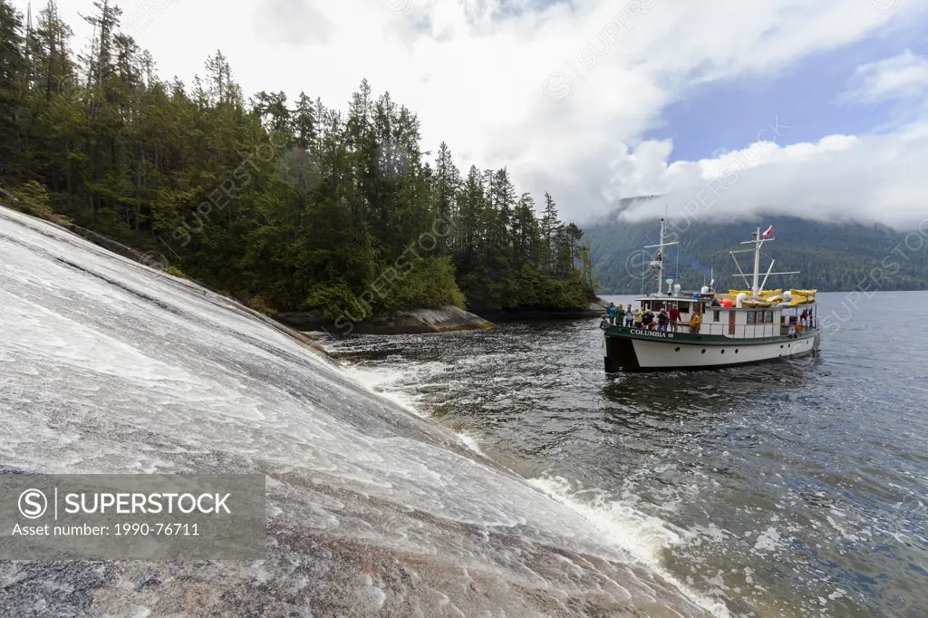 The Columbia III noses into a low angle waterfall in Tribune Channel for guests to take pictures while on a photo-tour in the Broughton Archipelago. B...