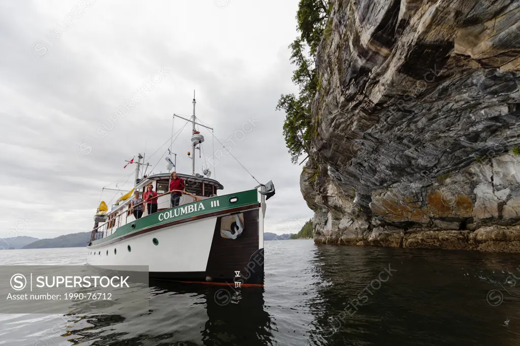 The Columbia III noses in and under a large overhanging cliff known as the deep sea bluffs for guests to take pictures while on a photo-tour in the Br...