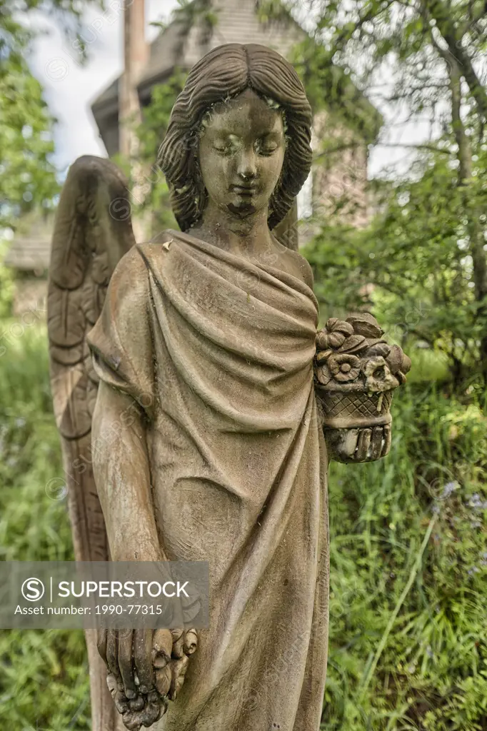 Carving of an angel with an old church behind it, Duncan, British columbia.