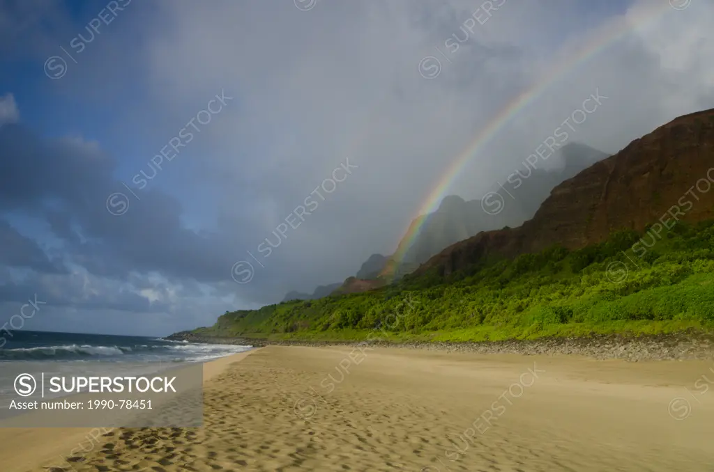 A rainbow arcs down from the mountains to the beach on the Kalalau trail, Na'Pali Coast, Kaua'i