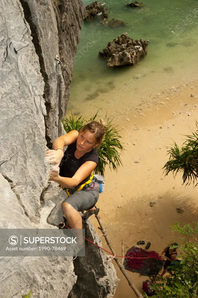 A young woman rock climbing in Lan Ha Bay, Vietnam