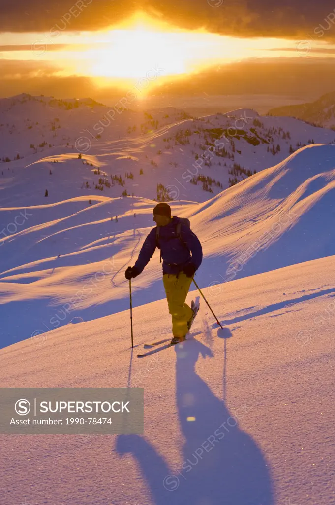 A male skier tours up on the ridgetops of Sol Mountain Monashee Mountains, British Columbia