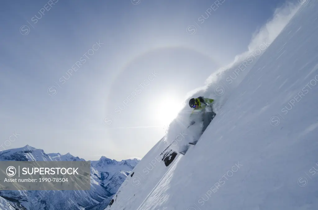 A skier in the Canadian Rockies of British Columbia above Icefall Brook, backlit by a sun halo