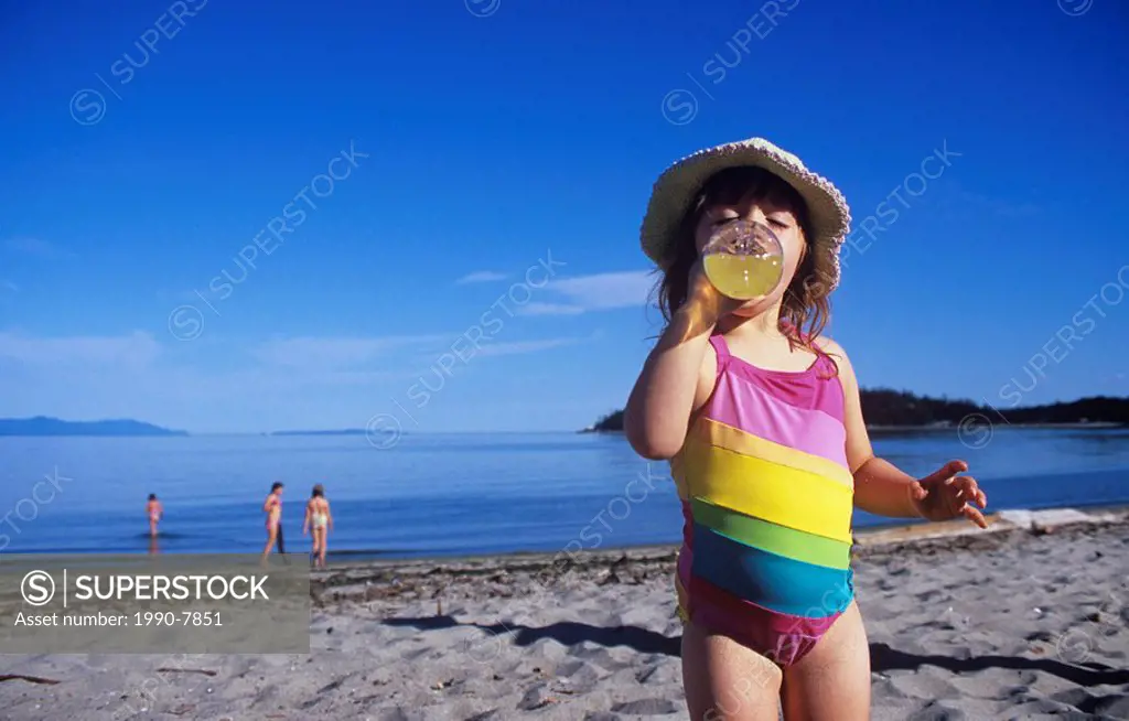 Young girl drinking beverage on hot day at beach, Vancouver, British Columbia, Canada