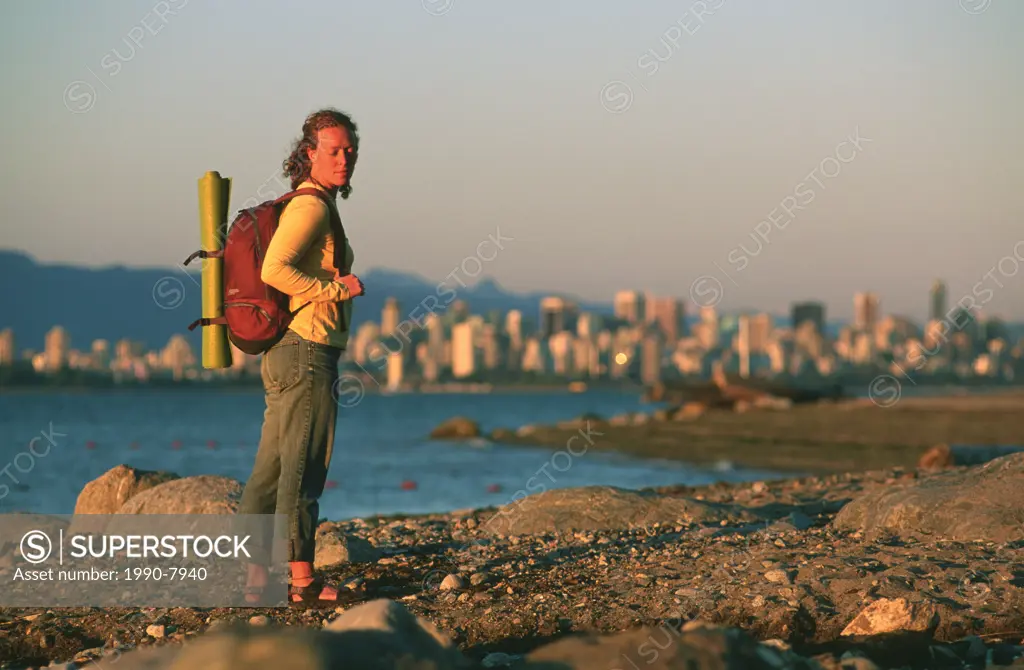 Woman walking at sunset on Jericho Beach, Vancouver, British Columbia, Canada.