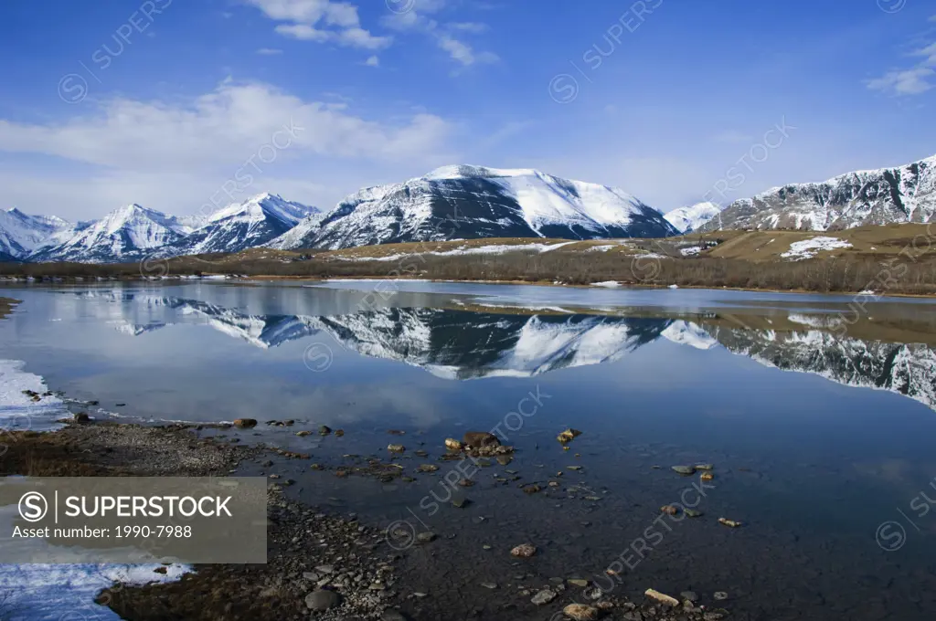 Reflection of area Mountains  Until the snowpac begins to melt the water level is down exposing gravel along the edges  As temperatures rise so will t...