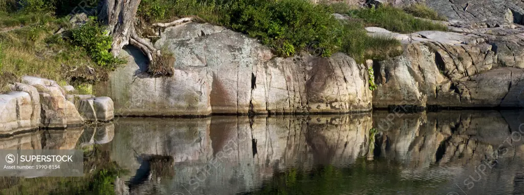 Granite outcrops reflected in pond, Killarney Provincial Park, Ontario, Canada