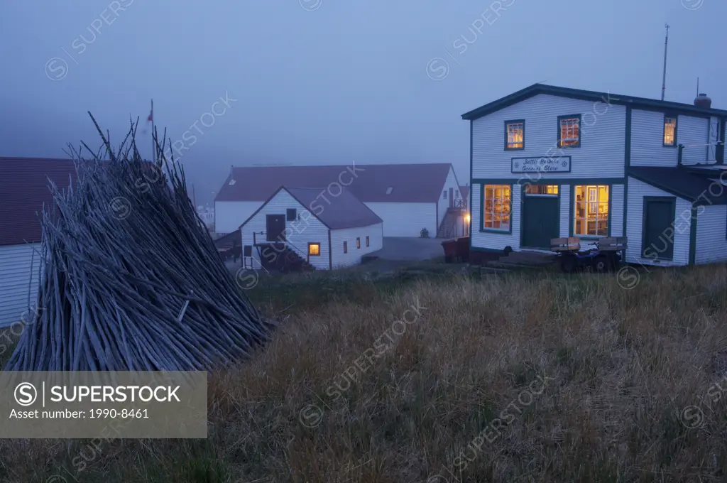 General Store and a stack of logs on a foggy evening in the historic fishing village of Battle Harbour situated on Battle Island at the entrance to th...