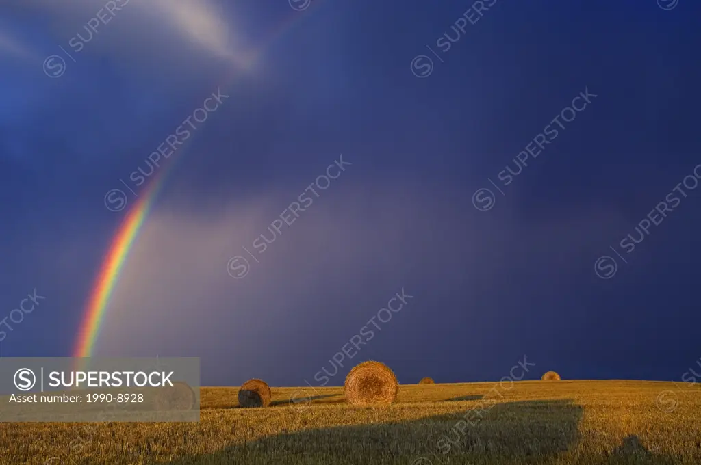 Rainbow and bales, stormy sky, Cypress River, Manitoba, Canada.