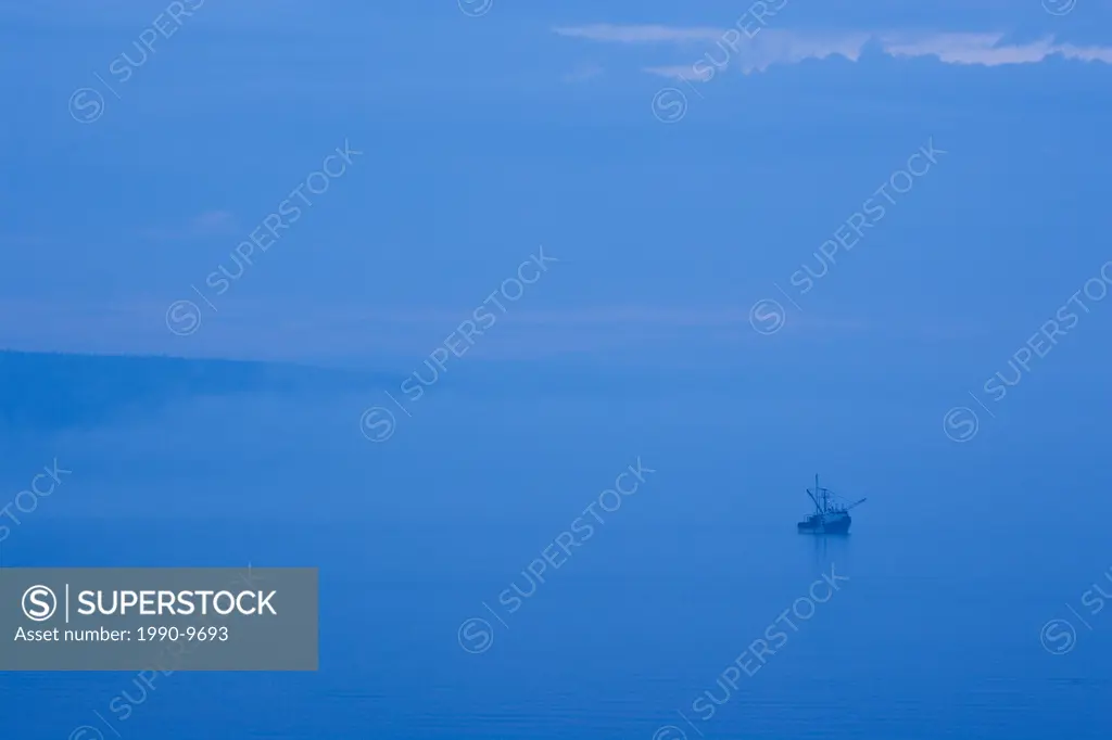 Scallop_dragger sits in Annapolis Basin while fishermen on board shuck scallops, Digby, Nova Scotia, Canada.