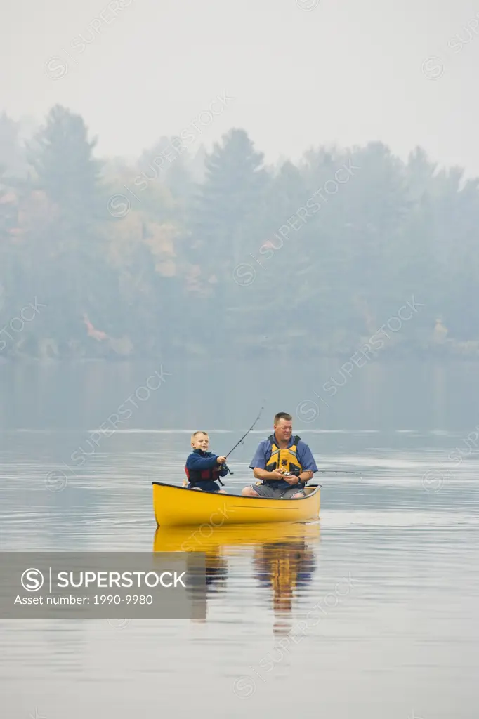 Young/middle_aged man fishing with son from canoe on Source Lake, Algonquin Provincial Park, Ontario, Canada.