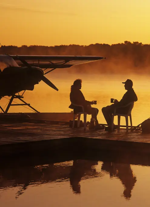 a couple relaxes on a float plane dock, Manitoba, Canada
