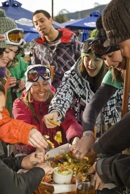 Group enjoys an apres-ski snack and drink on the outdoor deck of the Garibaldi Lift Company bar in Whistler, BC