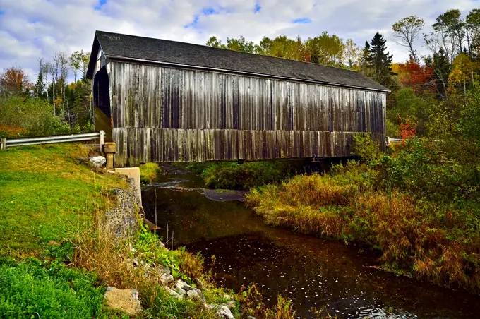 An autumn landscape view of the iconic wooden covered bridge spanning the Wards Creek near Sussex New Brunswick Canada