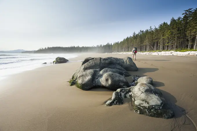 A female hiker trekking along the beach, West Coast Trail, Pacific Rim National Park Reserve, Vancouver Island, BC, Canada.